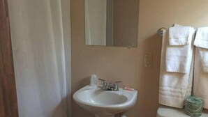 A bathroom with a white sink, a mirror above it, and a toilet with a green mat on top. - Black Forest Inn of Adamstown (Adamstown)