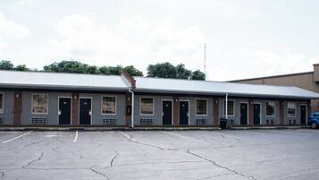 A motel with a row of rooms, a parking lot, and a blue car parked outside.