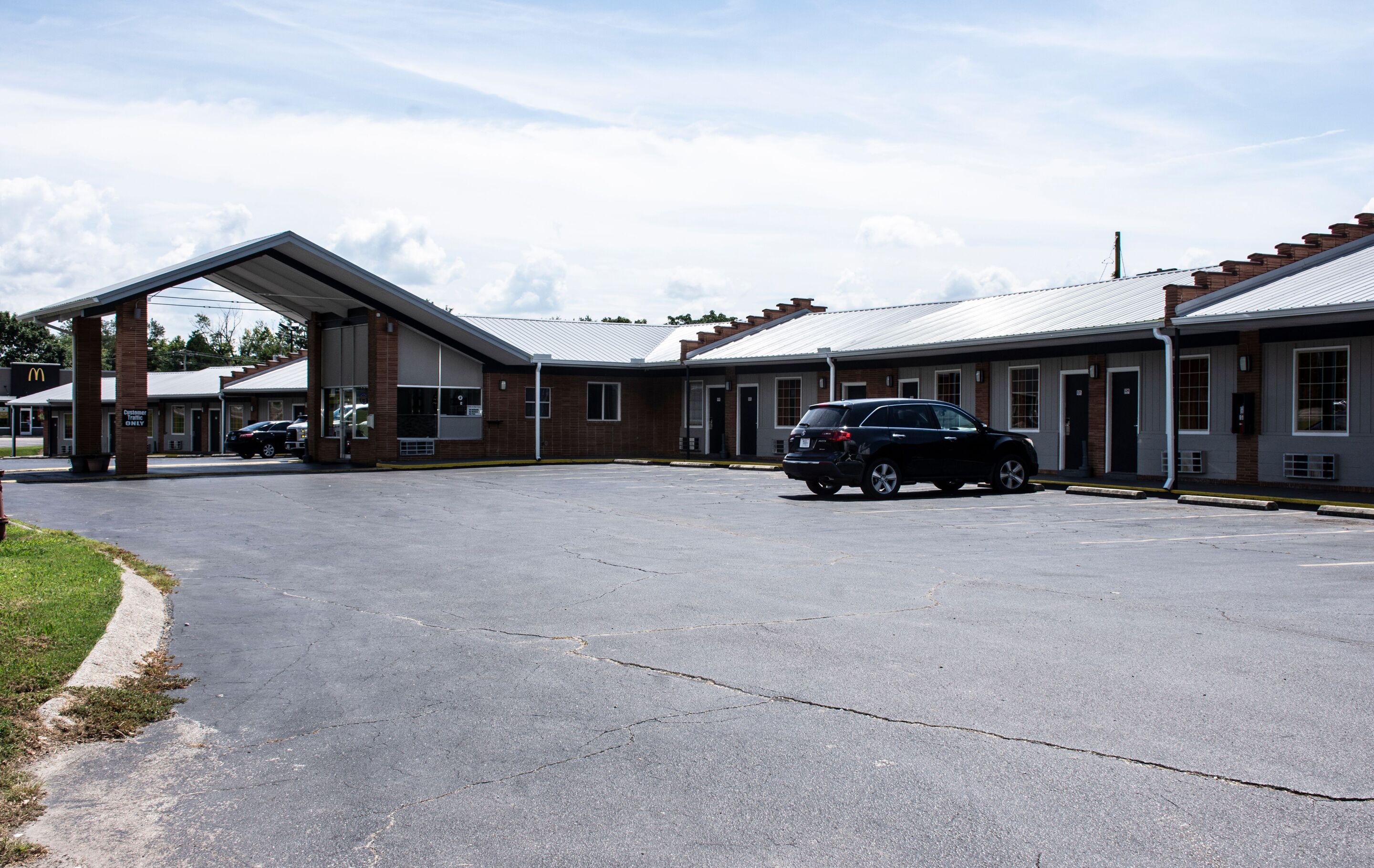 A motel with a covered parking area and multiple rooms.