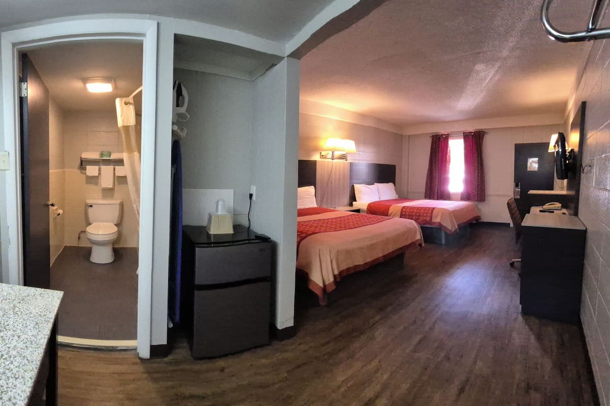 Habitació d'hotel amb bany, un llit, escriptori i mirall.