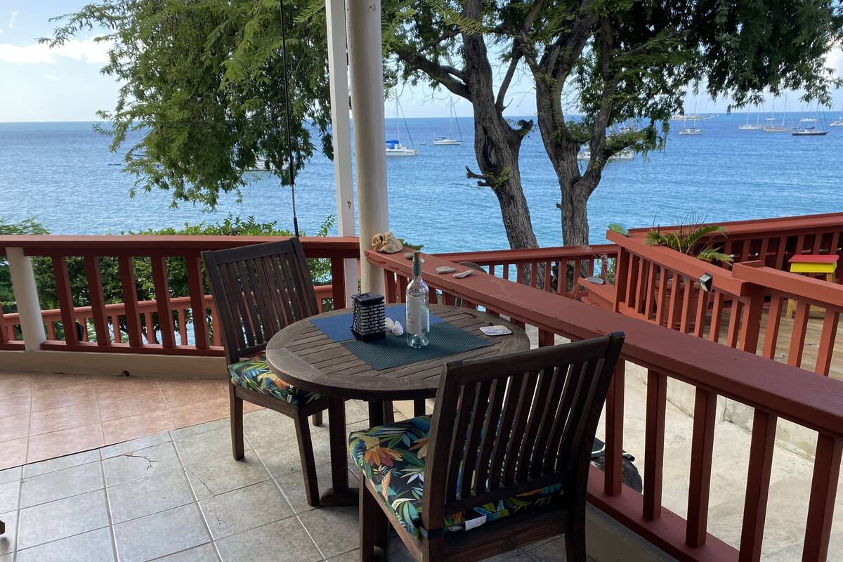 A wooden deck with a table and chairs overlooking a body of water with boats.