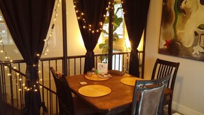 Un comedor con una mesa de madera, sillas negras y una barandilla.