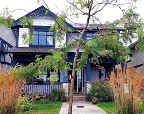A two-story house with a front porch, a small garden with various plants, and a mailbox. - Seagrass Guesthouse (Tsawwassen)