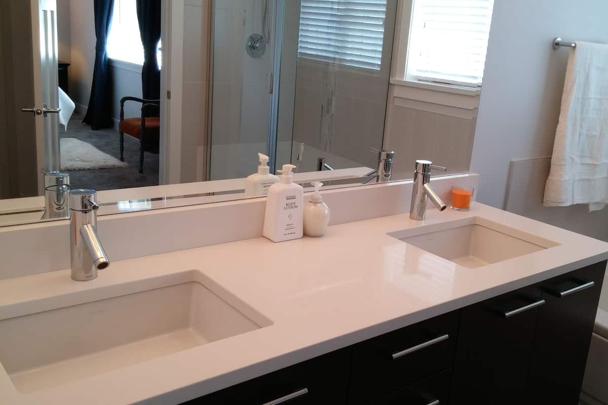 Une salle de bain moderne avec un double vasque, un grand miroir et une baignoire.
