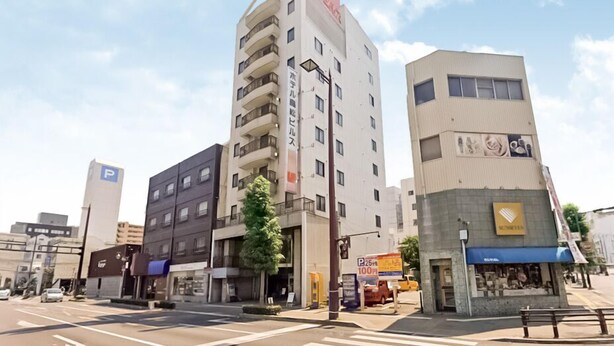 A multi-story building with a prominent Coca-Cola sign, a parking sign, and a small kiosk. - Hotel Takamatsu Hills (Takamatsu)