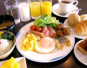 A breakfast plate with eggs, sausages, bacon, and tomatoes. - Hotel Tsubame Hills (Tsubame)