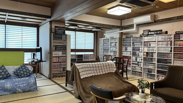 A cozy room with a bed, a small table, and a bookshelf filled with books. - Hotel Tsukuba Hills Gakuen Nishi Odori (Tsukuba)