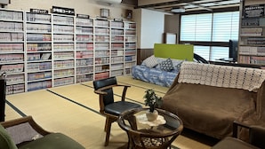 A library with bookshelves, a sofa, a chair, and a small table with a plant. - Hotel Tsukuba Hills Gakuen Nishi Odori (Tsukuba)