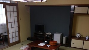 A traditional Japanese room with tatami flooring, a low wooden table, a television, a small cabinet, and a sliding door. - Hotel Tsukuba Hills Gakuen Nishi Odori (Tsukuba)