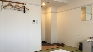 Une chambre d’hôtel équipée d’un lit, d’une armoire, d’un miroir et d’une petite kitchenette.