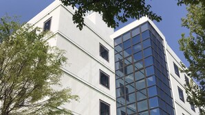 Un bâtiment moderne avec une façade en verre et un distributeur automatique de Coca-Cola à l’entrée.