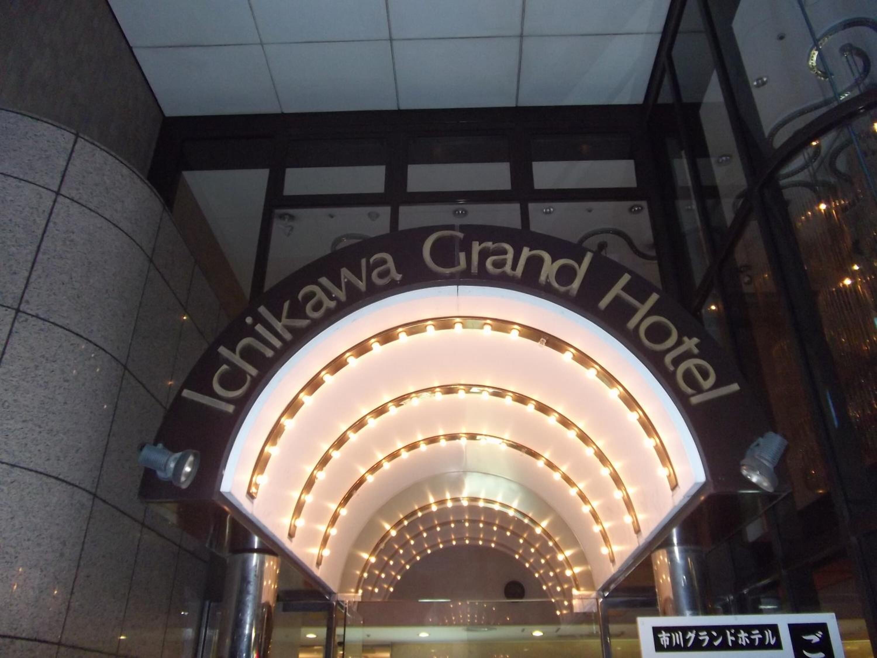 The entrance of the Ichikawa Grand Hotel with a distinctive arched sign and illuminated lights.