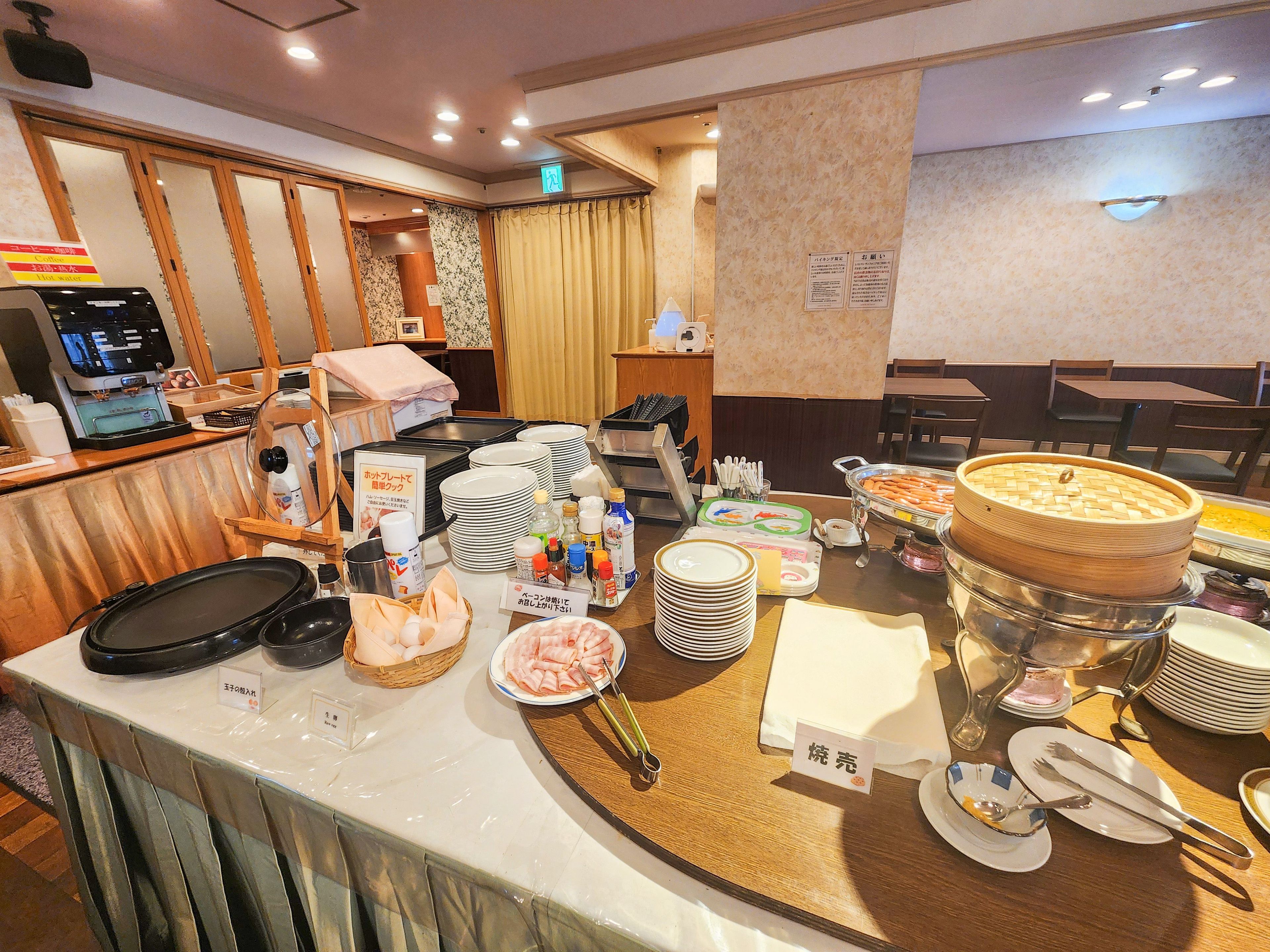 A buffet setup with various food items, plates, and utensils.