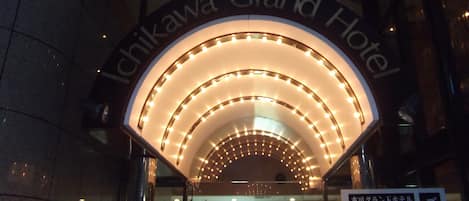 De ingang van het Ichikawa Grand Hotel, met een moderne, verlichte boog en een bord met Japanse tekst.