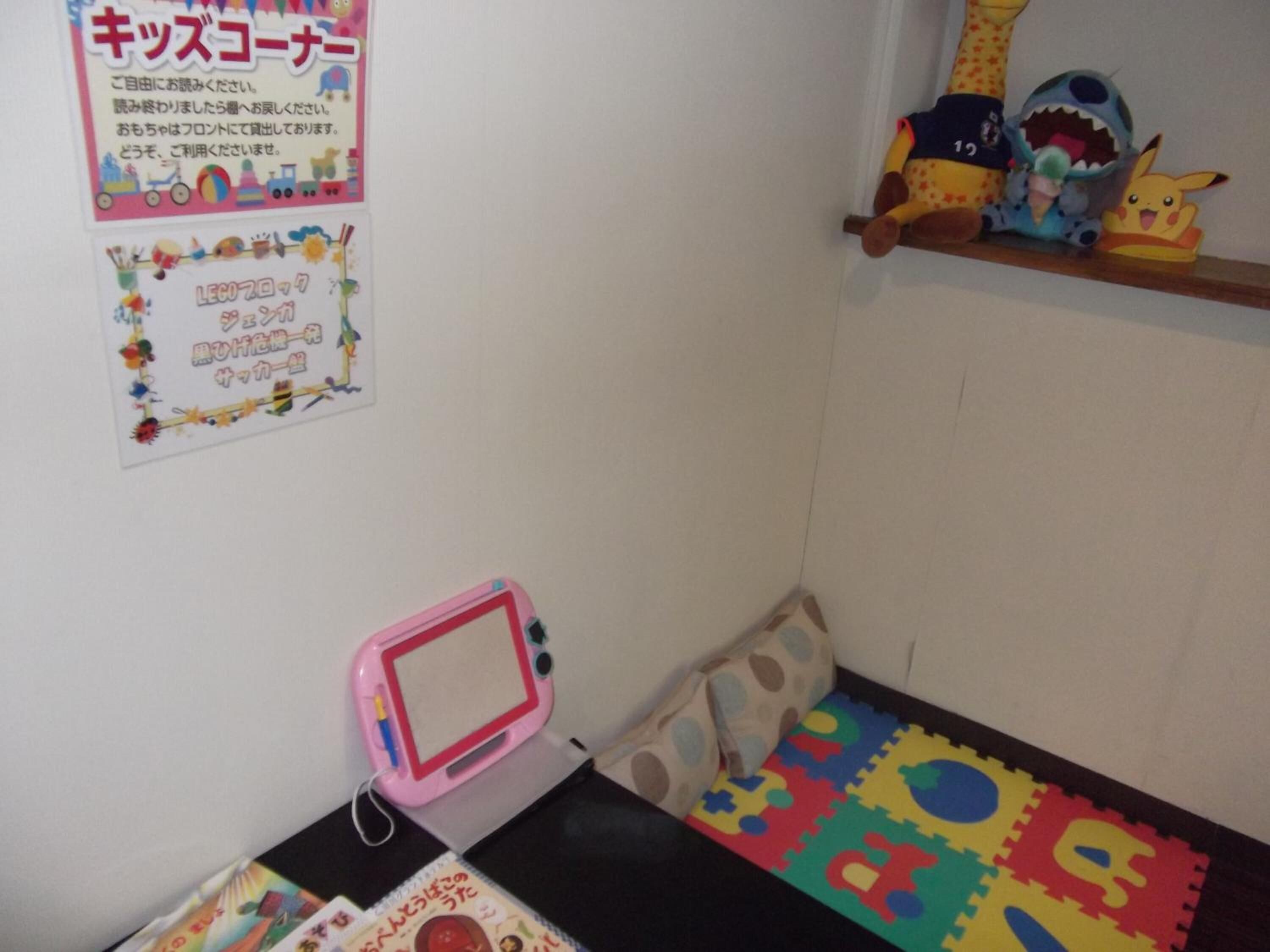 A child's playroom with a pink playpen, colorful foam mats, and a shelf with toys.