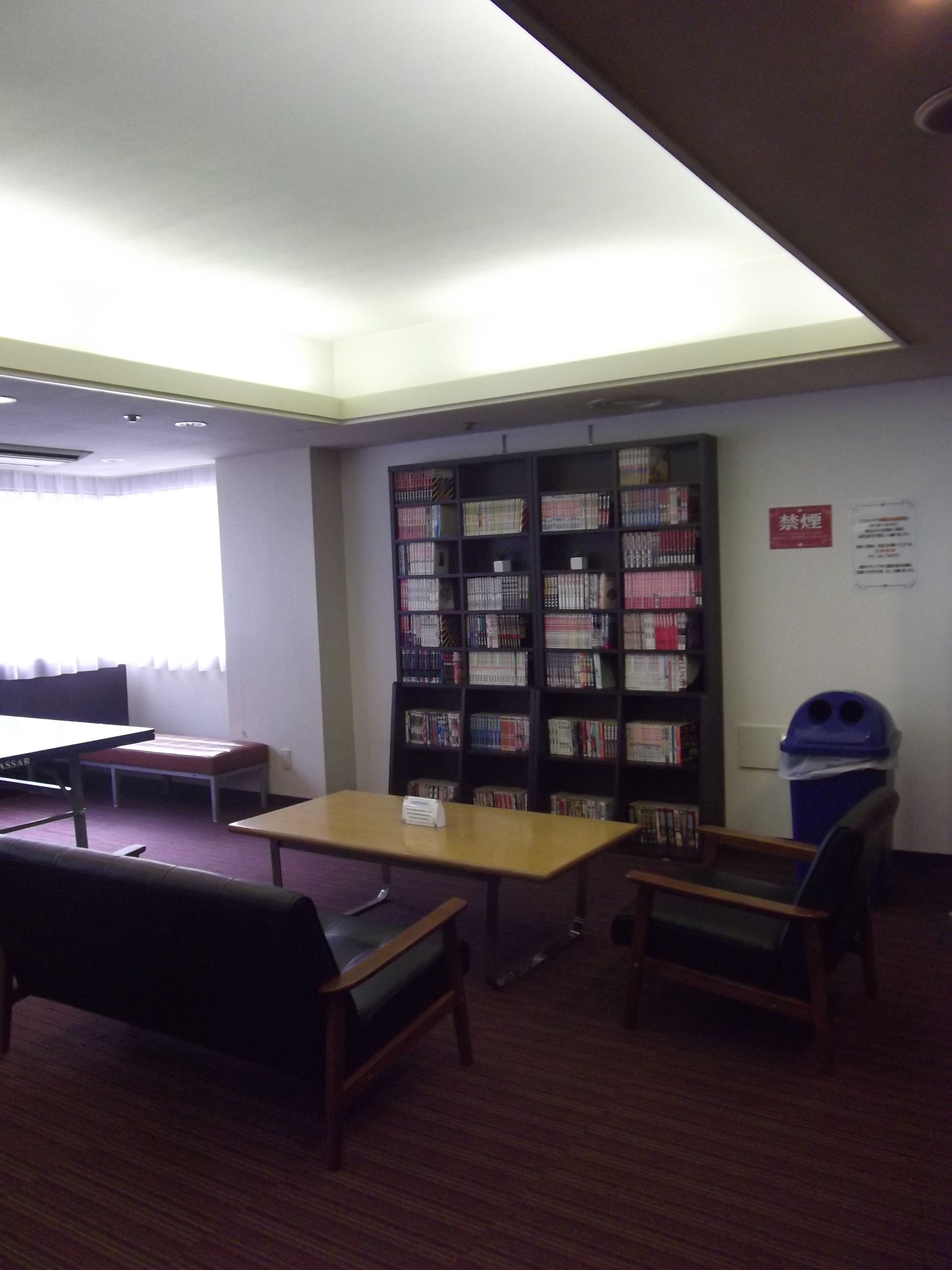 Une bibliothèque avec des étagères, une table et des chaises.