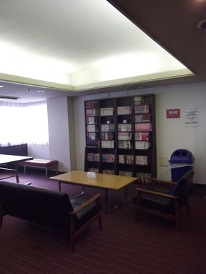 A library with bookshelves, a table, and chairs. - Ichikawa Grand Hotel (Ichikawa)