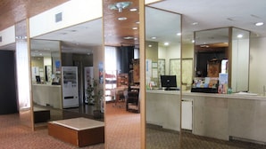 A reception area with a counter, a computer, and a small seating area. - Kai Resort Hotel (Fuefuki)