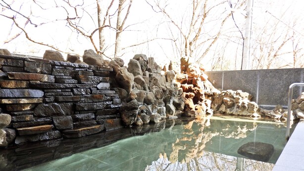 A stone wall with a clear pool reflecting trees. - Kai Resort Hotel (Fuefuki)