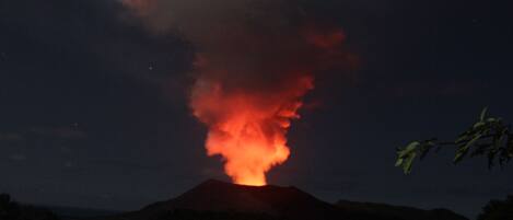 Ein Vulkan mit einer leuchtenden Lavafontäne bei Nacht.