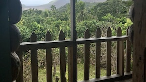 Un balcón de madera con vistas a un paisaje exuberante y una montaña a lo lejos.