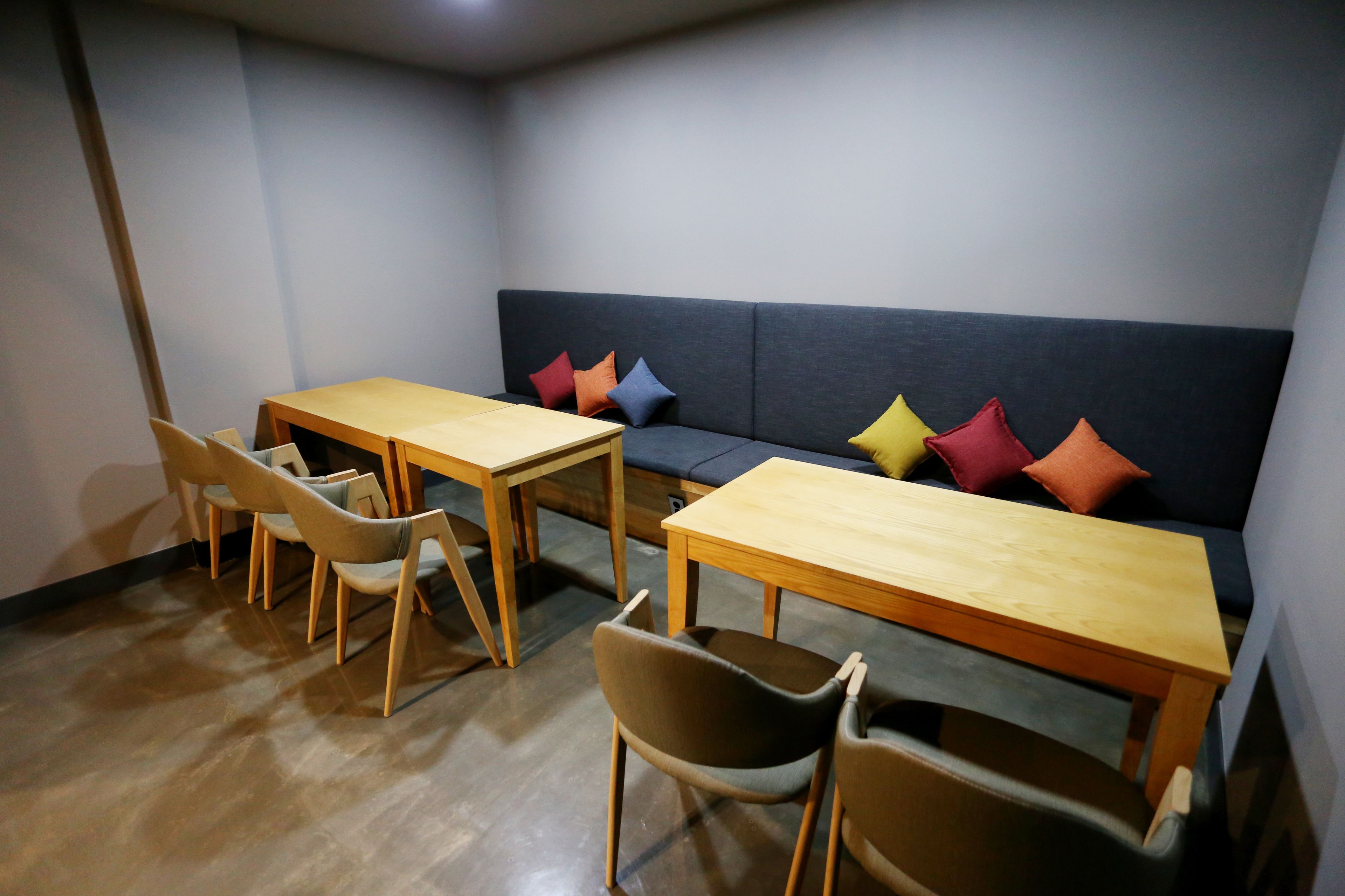Una habitación con un sofá, dos mesas de madera y cuatro sillas.
