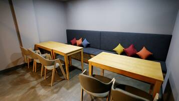 Una habitación con un sofá, dos mesas de madera y cuatro sillas.