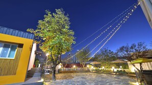 A courtyard with stone flooring, outdoor seating, and string lights. - WITH U Hotel & Guesthouse (Sokcho)
