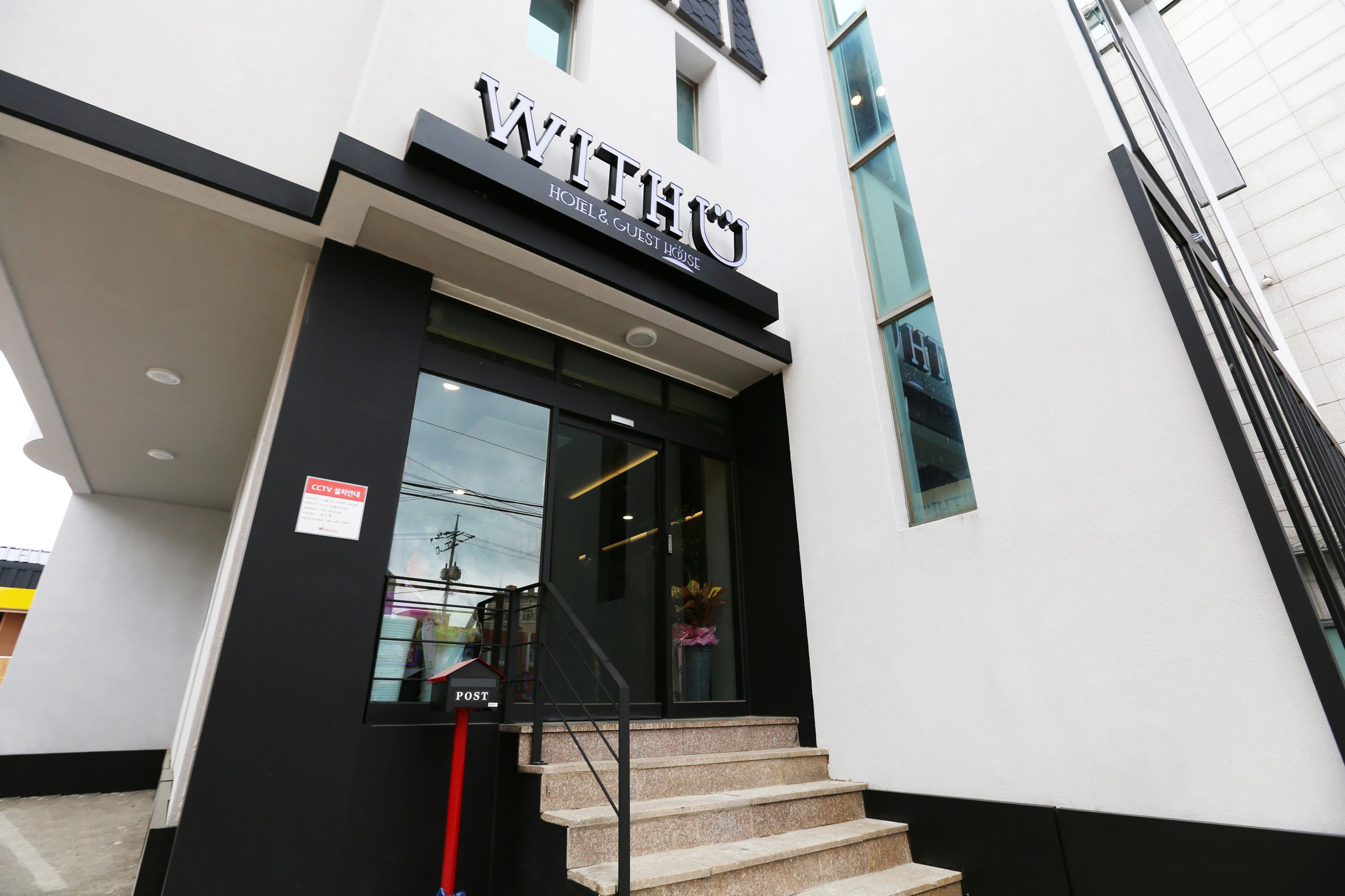 A hotel entrance with a sign reading "WITHIN HOTEL & GUEST HOUSE".