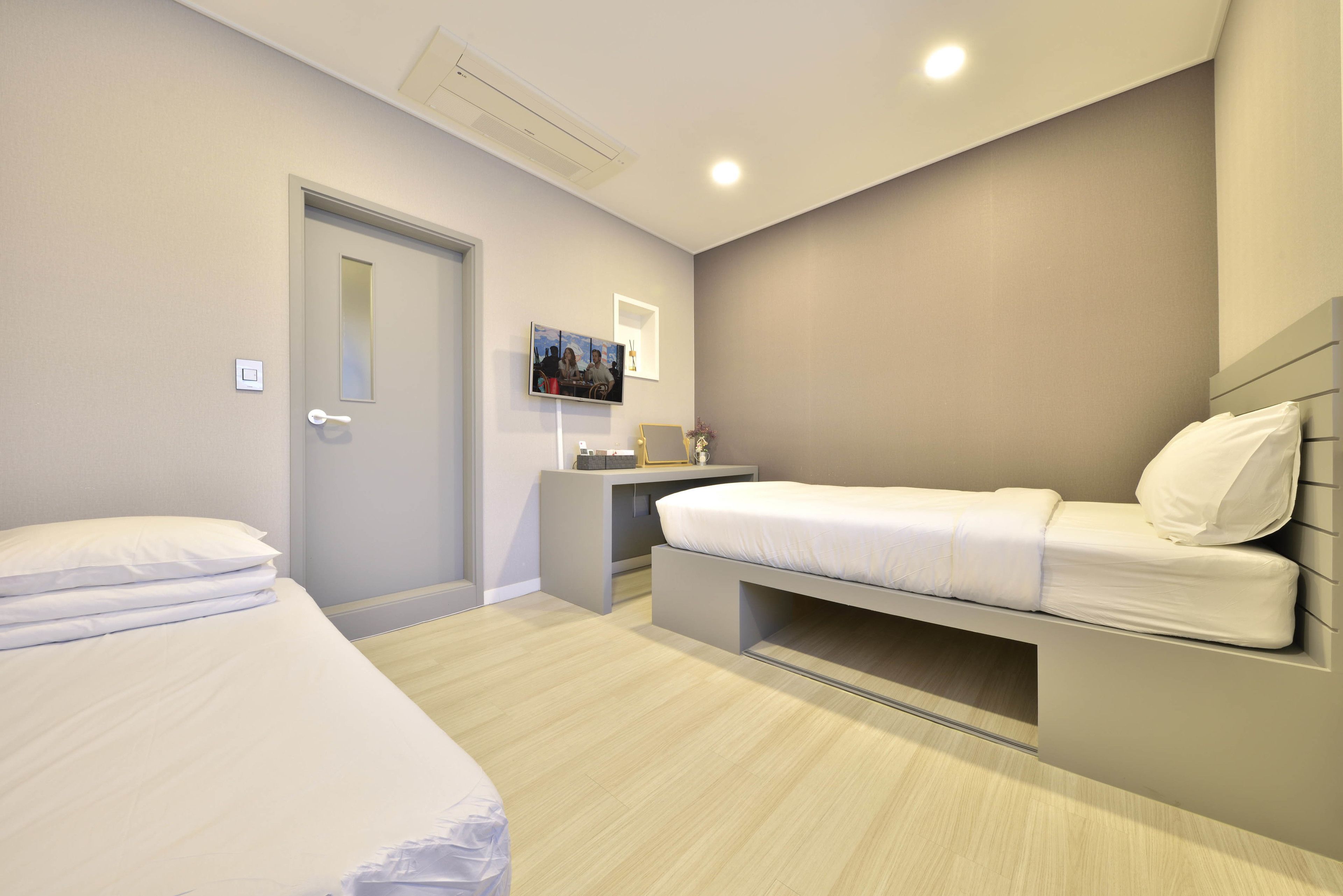 A modern bedroom with a bed, bedside table, and a desk with a chair.