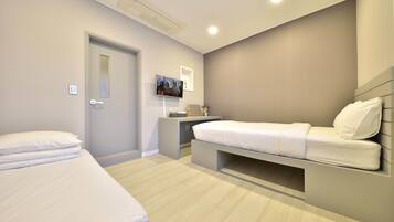 A modern bedroom with a bed, bedside table, and a desk with a chair.