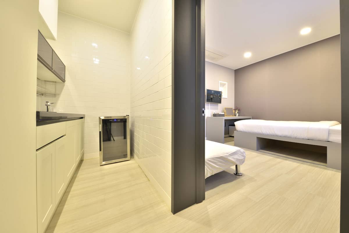 A modern hotel room with a kitchenette, a bed, and a small seating area.