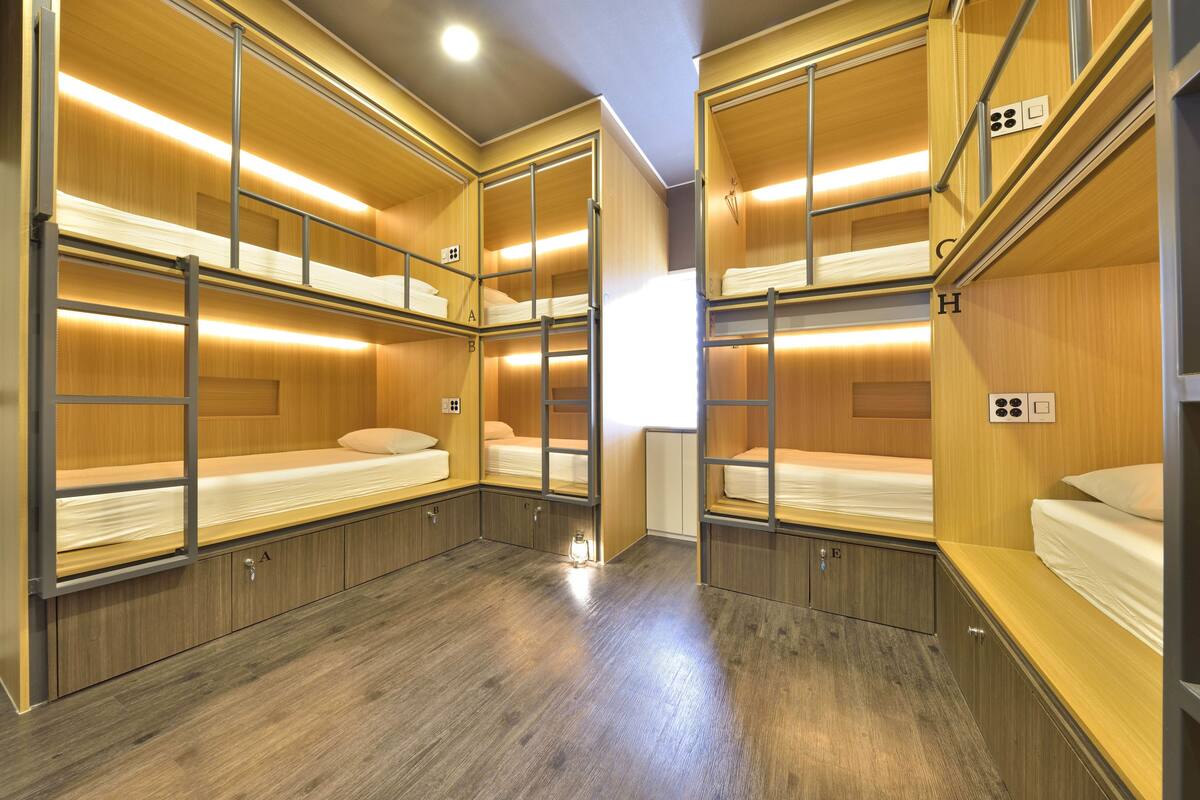 A bunk room with wooden bunk beds, metal railings, and a wooden floor.
