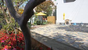 Un patio con suelo de piedra, una cerca de madera y un paraguas amarillo.