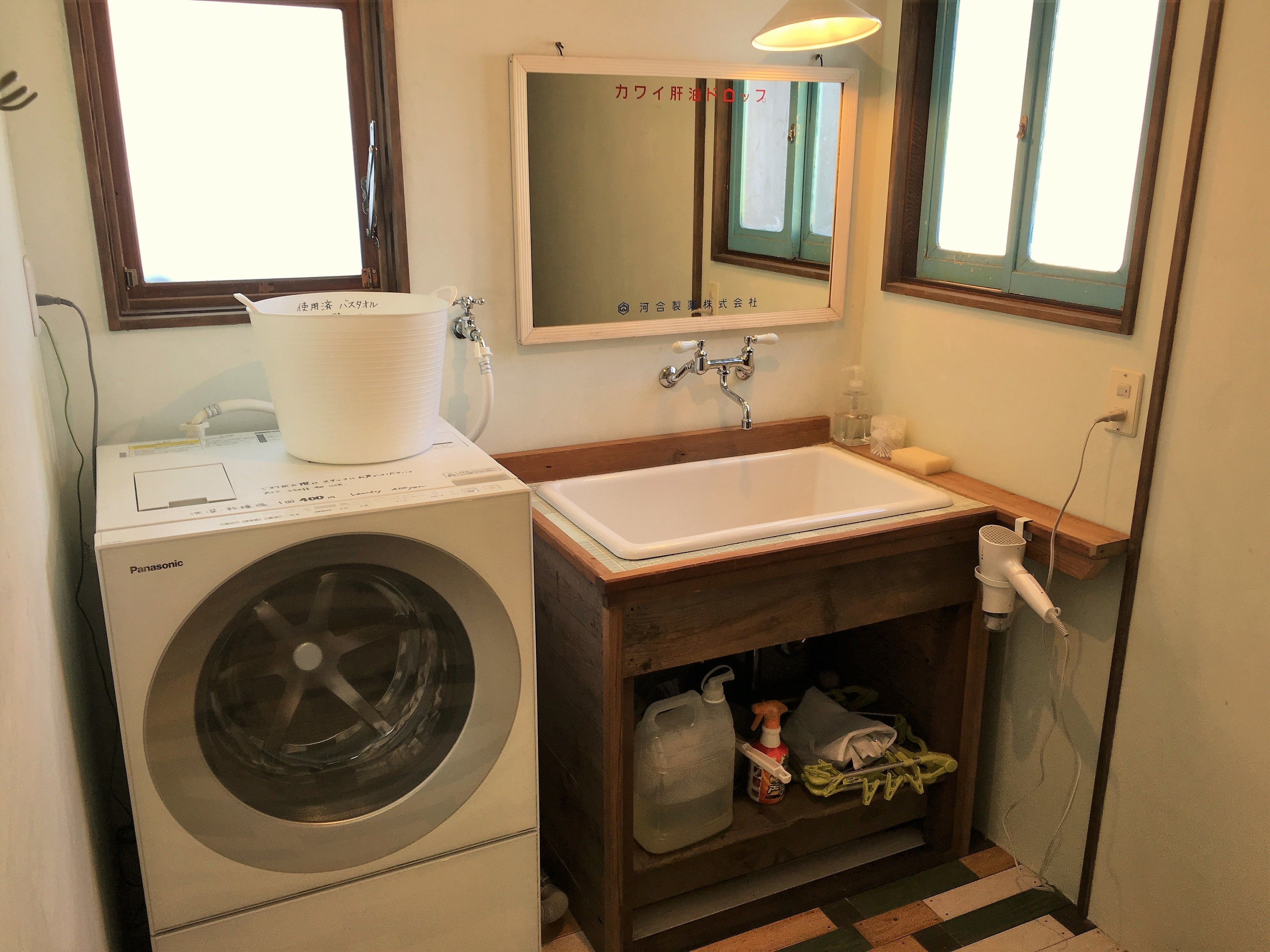 Une petite salle de bain équipée d’un lave-linge, d’un évier et d’un miroir au-dessus de l’évier.