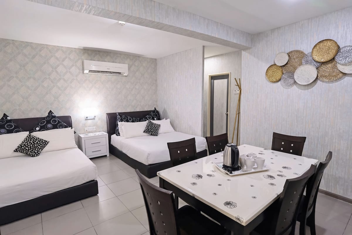 A hotel room with two beds, a dining table, and a decorative wall piece.
