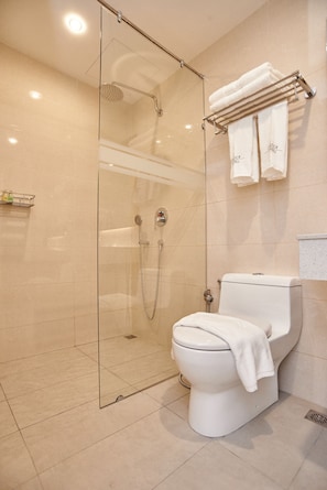 A modern bathroom with a glass-enclosed shower, a white toilet, and a towel rack with two towels. - Corsica Hotel (Kulai)