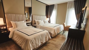 A hotel room with two beds, a desk, and a TV. - Corsica Hotel (Kulai)