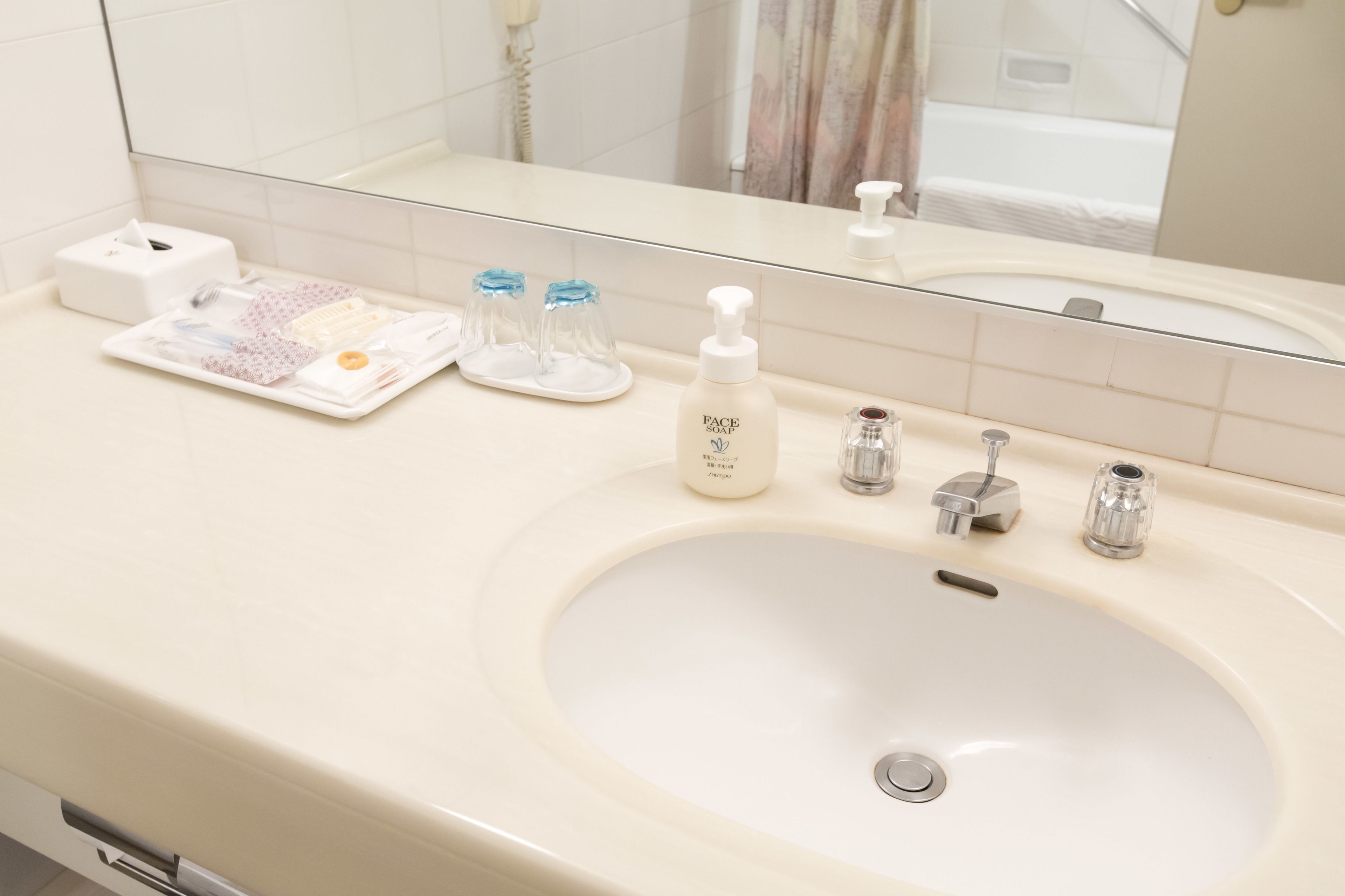 A bathroom with a white sink, a mirror, and toiletries on the counter.