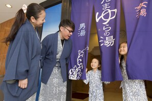 En grupp människor i traditionella dräkter som står framför lila banderoller med japansk text.