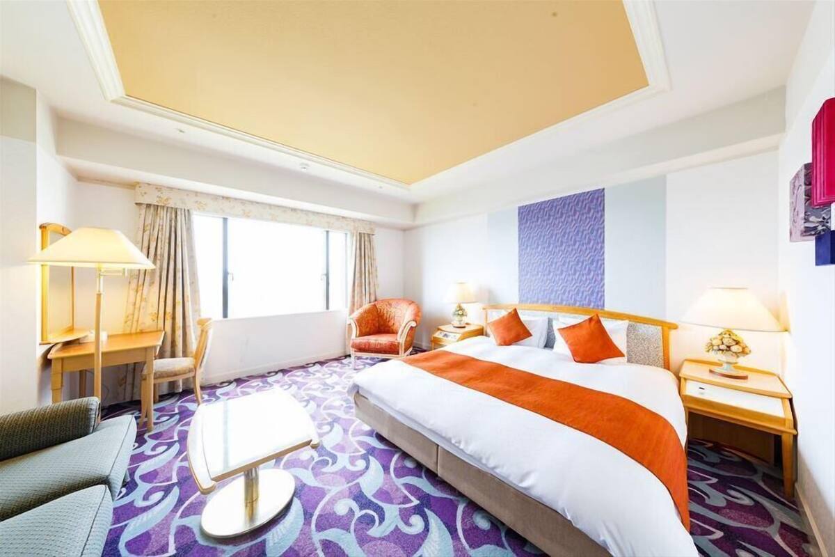Una habitación de hotel con una cama grande, un escritorio, una silla y una mesita.