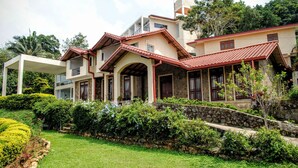 A multi-story house with a stone facade, red-tiled roof, and a well-maintained garden with various shrubs and flowers. - The Kandyan Villa (Kandy)
