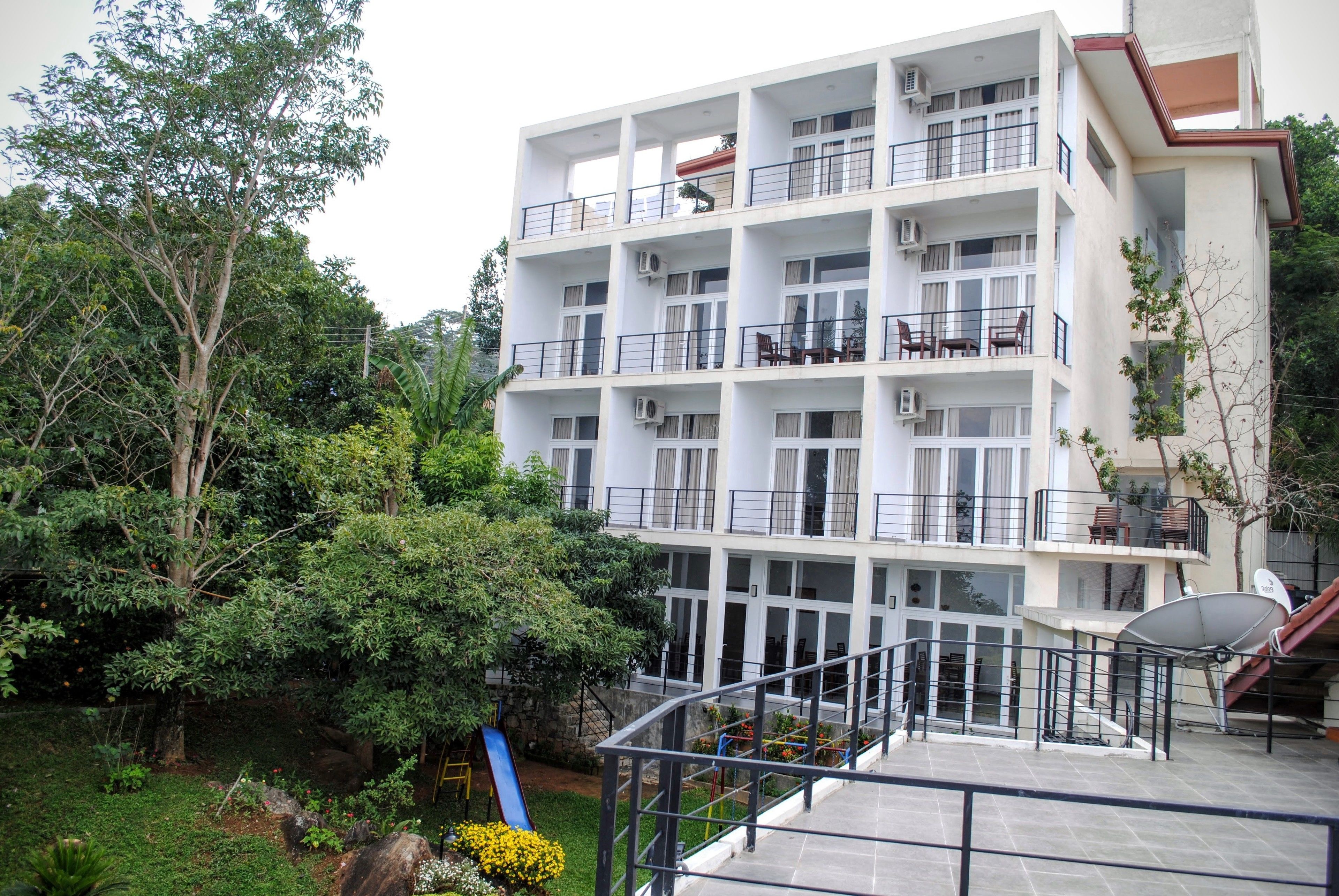 A multi-story building with balconies, a satellite dish, and a slide in the courtyard.