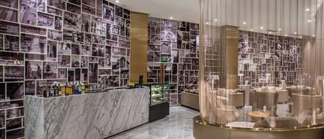 A hotel lobby with a marble reception desk, a seating area with sofas, and walls adorned with black and white photographs.