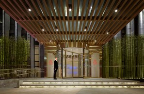 A modern hotel entrance with a revolving door, glass walls, and a bamboo garden. - Skytel Hotel Chengdu (Chengdu)