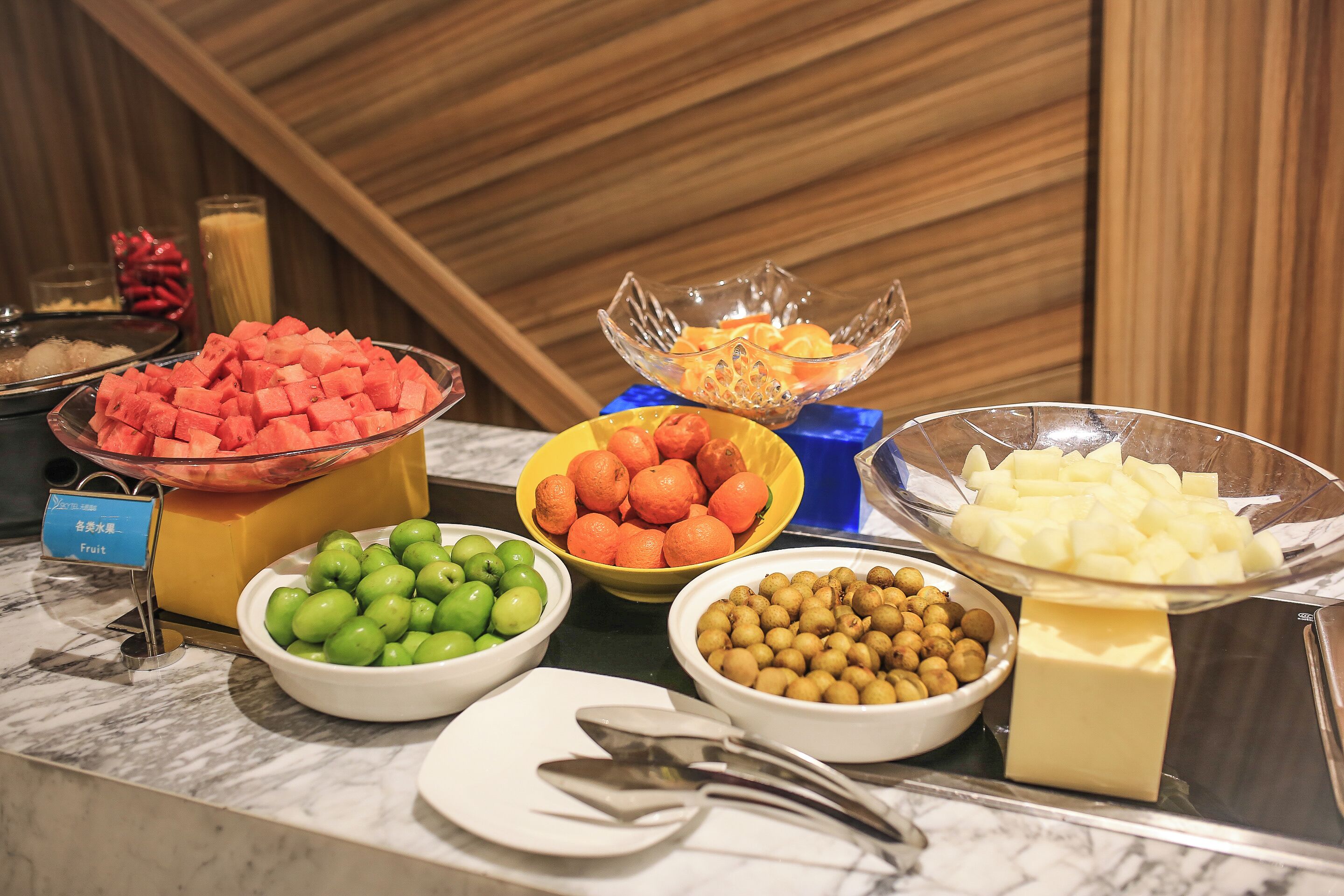 Un bufé con diversas frutas y una pieza de queso.