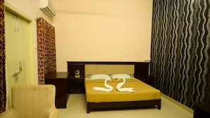 Une chambre d’hôtel avec un lit, une chaise, une table de chevet et un mur orné d’un motif ondulé.