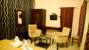 Une chambre d’hôtel comprenant un lit, deux fauteuils, un bureau, une télévision et un miroir.