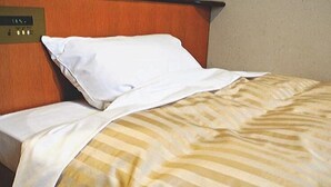 Une chambre d’hôtel avec un lit, un panneau de commande et un mur sobre.