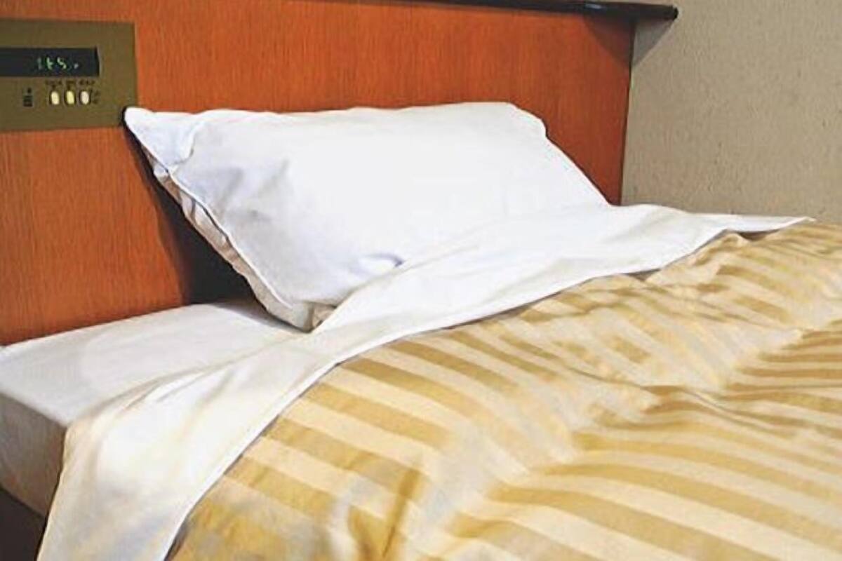 Ett hotellrum med en säng, en kontrollpanel och en enkel vägg.